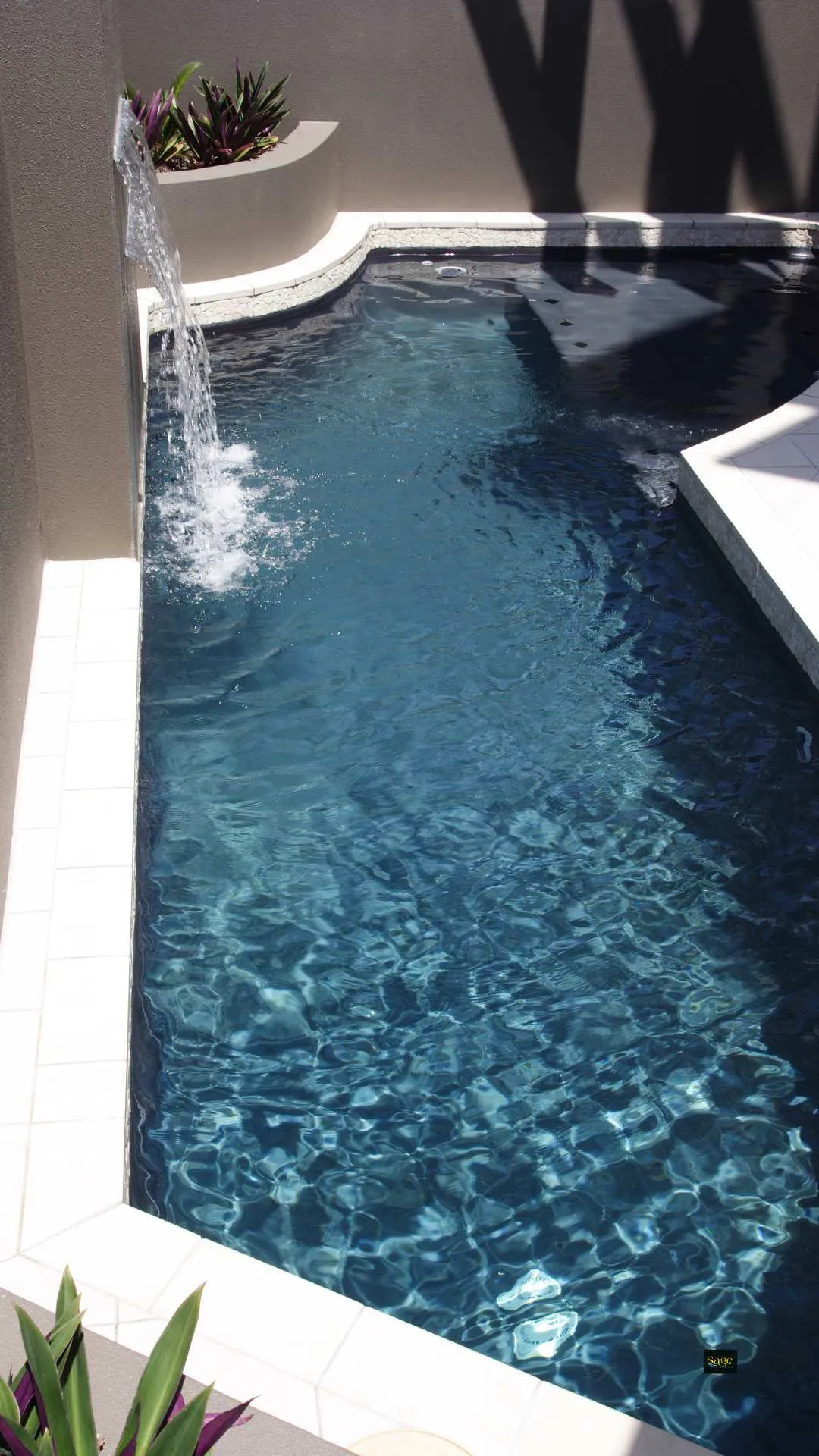 small designer pool with wall fountain and baja shelf